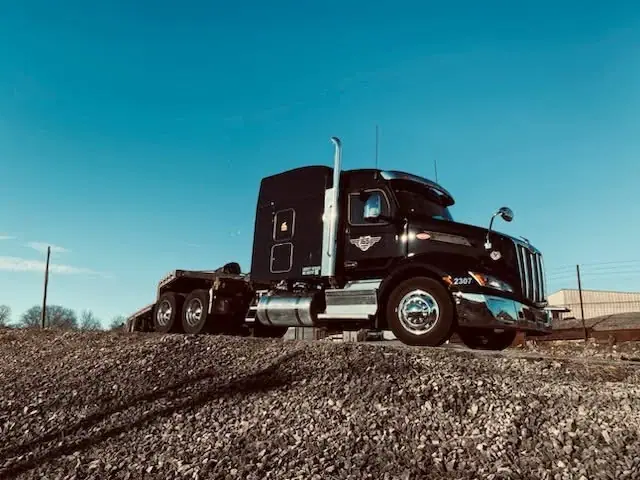 An I65 Transport Peterbilt with a lowboy trailer on a gravel lot