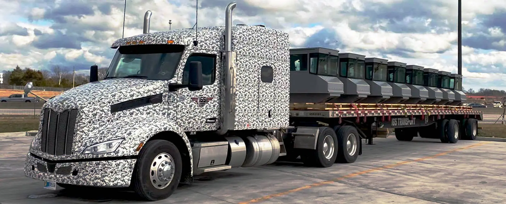 An I65 Transport Peterbilt pulling a loaded flatbed