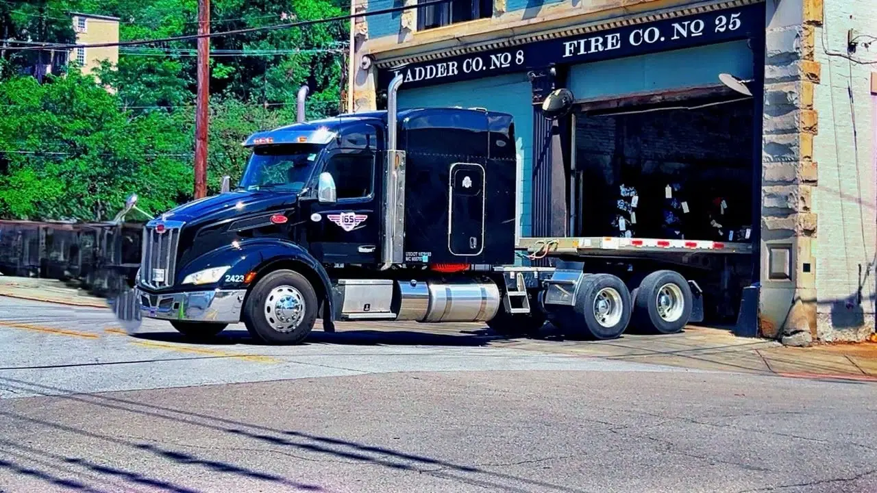 An I65 Transport Peterbilt pulling an empty flatbed through town